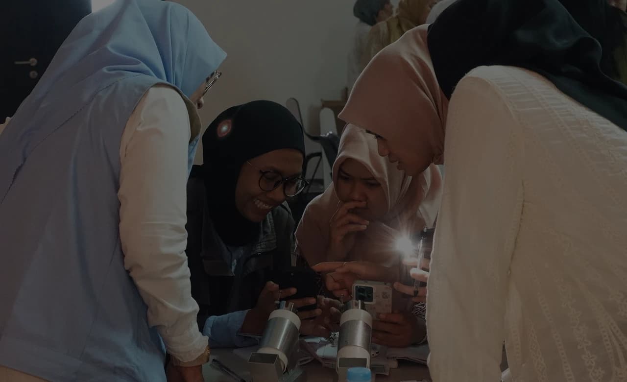 Healthcare workers gathered around a smartphone during a HerLens session